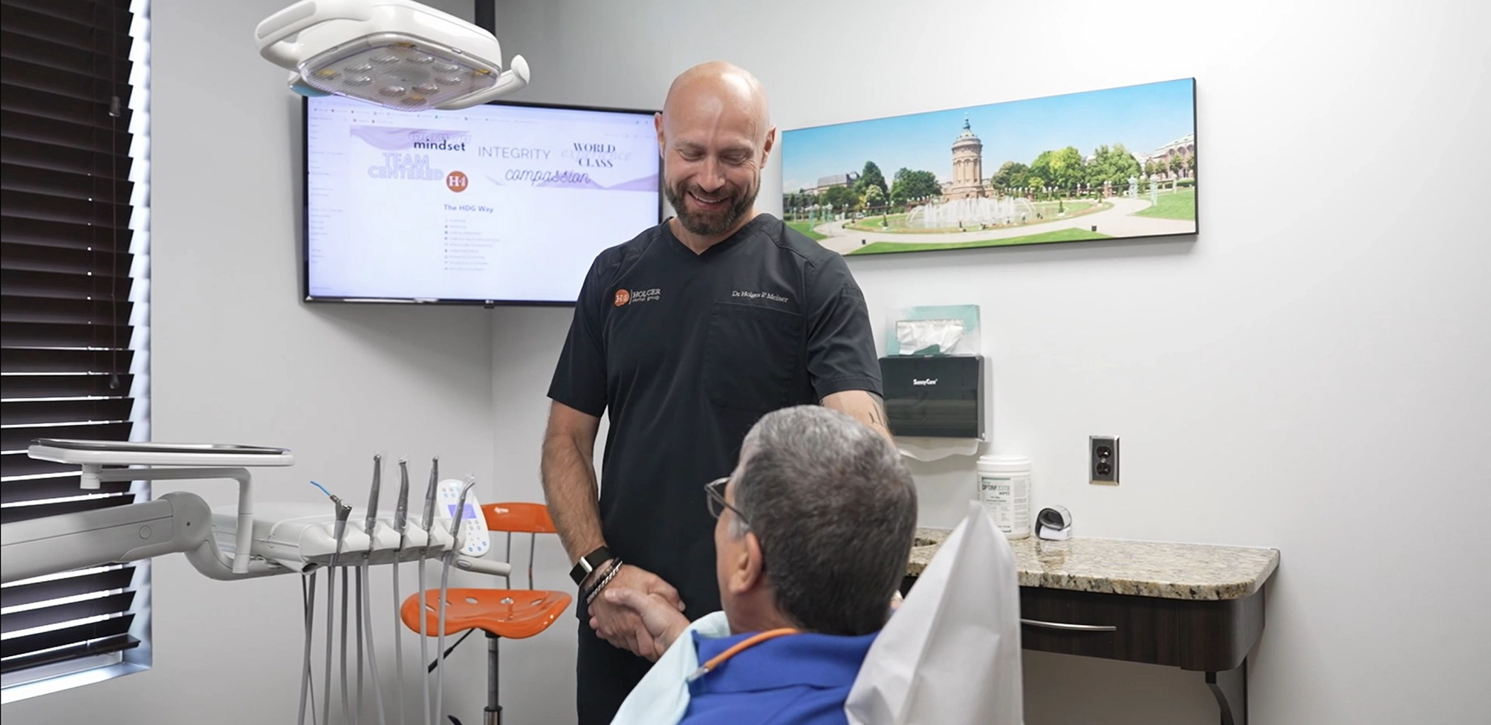 Doctor Holger shaking hands with a man in the dental treatment chair